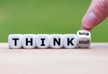 Hand turns a dice and changes the expression "think small" to "think big".